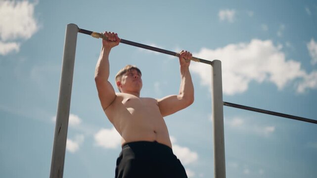 fitness pursuit outdoors, brave firefighter candidate practicing pull ups outside, dedicated firefighter apprentice executes disciplined pull ups beneath bright sunlight in open park area