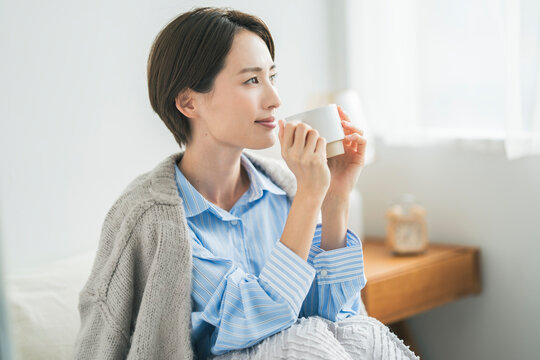 寝室で温かい飲み物を飲む女性