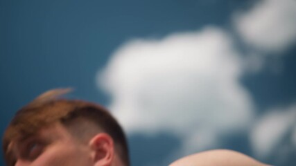 young man performing pullups on outdoor bar against bright blue sky, close camera angles capture effort and breathing, athletic trainee pushing endurance, park workout atmosphere with coach presence,