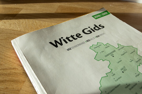 AALST, BELGIUM, 2 DECEMBER 2025: Illustrative editorial image of an obsolete paper phonebook the 'Witte Gids', White Pages telephone directory of Flanders, which after 2020 is only available digitally