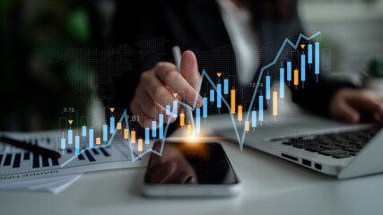 A businessperson examines stock market trends using digital graphs while working on a laptop and smartphone in a modern office setting. Focus on analysis and growth strategies. Gantry