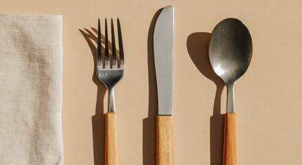 Simple wooden handled fork knife and spoon set on a textured background