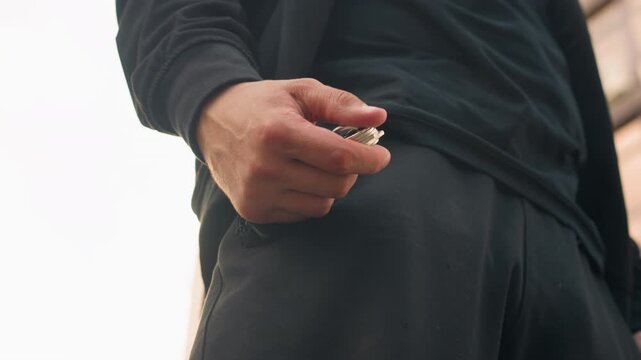 person picking keys outside doorway, urban resident retrieving keys from pocket outside building entrance, city dweller in athletic attire preparing to take keys from their pocket outside building