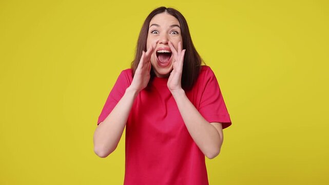 Excited happy fun young woman wear pink t-shirt casual clothes scream hot news about sales discount with hands near mouth hurry up isolated on plain yellow color background studio. Lifestyle concept