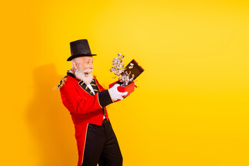 Circus magician in red costume discovers joyful gift moment on a bright yellow background during a holiday show