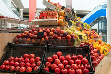 A vibrant, well-lit display of fresh pomegranates, apples, and assorted fruit