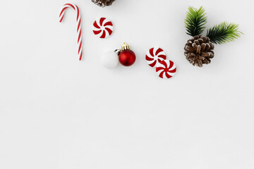 Minimalist Christmas Composition with Peppermint Candies and Pine Cone on White Background