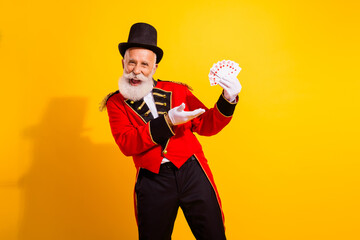Circus magician in red jacket performs dazzling card tricks on a bright yellow background for a lively fun holiday show
