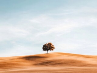 Majestic tree stands alone on golden hills under a clear blue sky during a serene autumn afternoon