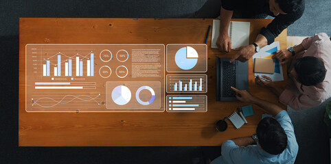 A business team engages in data analysis, showcasing graphs and statistics on a table. The setting emphasizes collaboration and modern technology in a professional workspace. Gantry
