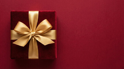 luxury gold gift box with glitter ribbon on deep red background