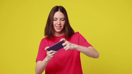 Gambling excitable young woman wear pink t-shirt casual clothes use play racing app on mobile cell phone hold gadget smartphone for pc video games isolated on plain yellow background Lifestyle concept