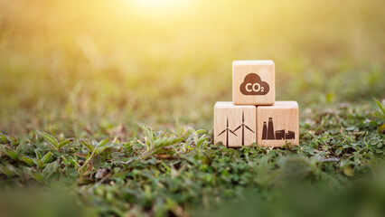 Wooden cubes with CO2 and renewable energy icons on green grass nature background.