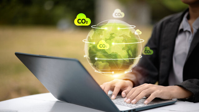 Business person using laptop with global CO2 emission and green earth hologram.
