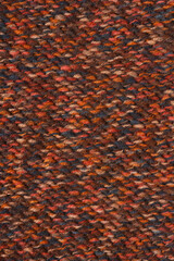A full-frame, vertical macro texture of dark, speckled knitting in rich autumnal colors like brown, rust, and orange, showing the close-up weave pattern