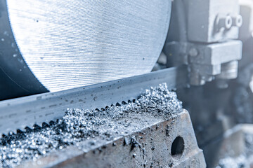 Close-up scene: A band saw cutting metal shaft parts in blue tones. copy space