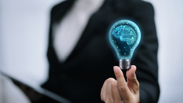 Business person holding light bulb with glowing digital brain for artificial intelligence concept.