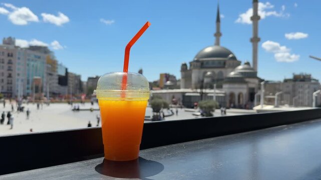 Fresh orange juice on street cafe table with view of Taksim Square and mosque on sunny summer day