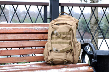 Tactical backpack resting on park bench during winter