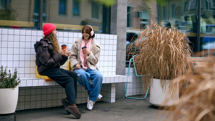 Group of friends enjoying winter drinks and relaxed conversation outside cafe. Concept of lifestyle...
