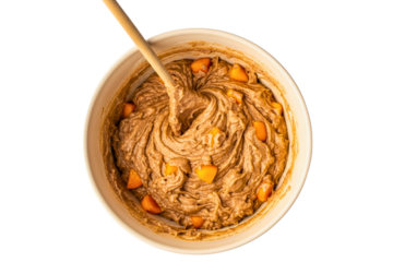 Ceramic mixing bowl filled with raw cake batter and fruit pieces on a transparent background