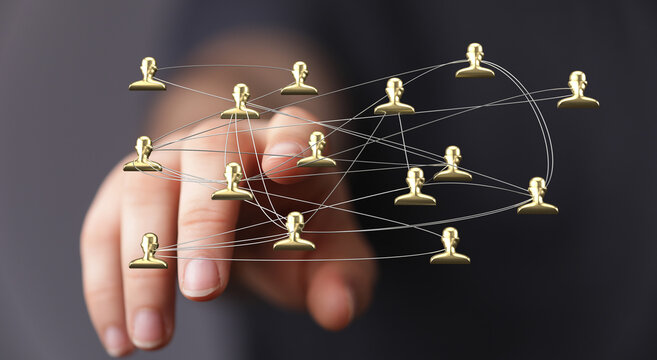 Hand reaching towards a network of connected golden people icons, representing social connection, communication and global concepts - Powered by Adobe