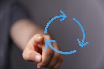 A hand pointing towards blue circular arrow symbol, representing process, cycle, or concept of data flow and connections