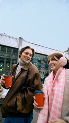 Friends sharing hot beverages outside glass storefront in winter. Concept of retail hospitality...