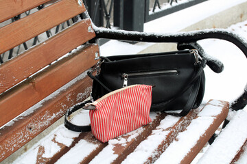 Two bags forgotten on snowy park bench in winter