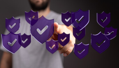 A person's hand interacting with virtual shield icons, symbolizing protection and digital security. The image conveys concepts of ver