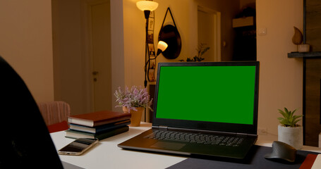 Modern home office featuring a laptop with a green screen on the table, perfect for crafting digital content and engaging in remote work.