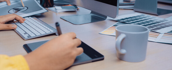 A vibrant creative workspace featuring a designer focused on using a digital tablet, accompanied by a computer and color palettes, embodying modern graphic design practices. SACTR