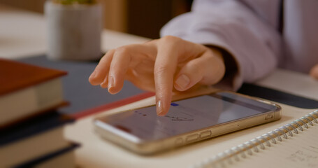 Close up view of a woman's hand as she uses her finger to sign on a smartphone screen. This moment captures the modern way of digital signing in an office environment.