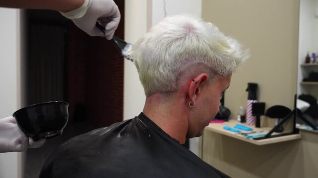 Profile shot of a man receiving a third bleaching application as hair colour shifts toward white
