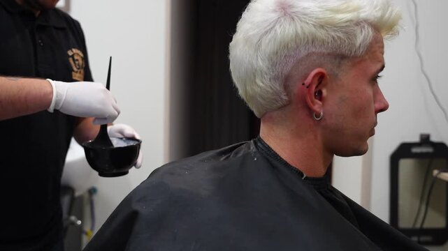 Medium shot of client nodding as hairdresser explains bleaching while mixing product in a small bowl
