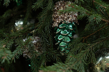 Decorated Christmas tree featuring green pine cones and silver ornaments, close up.