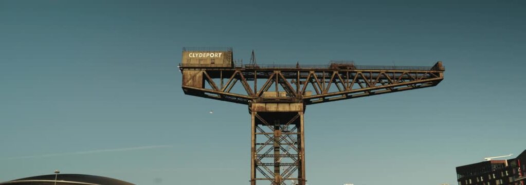 Cinematic Anamorphic 50mm Ultra-Wide: Finnieston crane against blue sky with birds flying across in fore ground 
