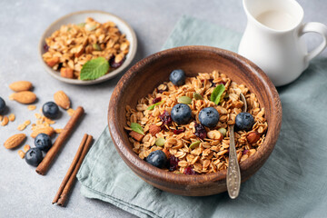 Homemade crunchy oat honey granola with raisins and nuts in wooden bowl, rich in fiber breakfast cereals