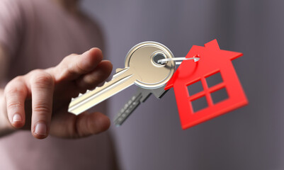 A hand presents keys to a new house, symbolizing home ownership, real estate, and the dream of owning a property.