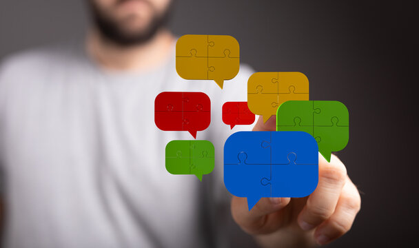 Abstract image of a person touching colorful speech bubbles made of puzzle pieces. Concept of teamwork, communication and brainstorming ideas.