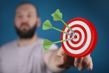 Close up of a man with a beard hitting the bullseye with darts, achieving goals and success concept.