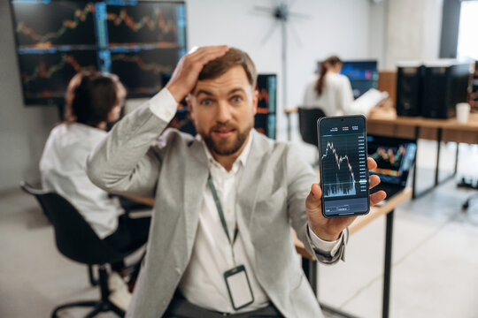 Worrying, showing graph on phone. Business people are working with stock market exchange in office