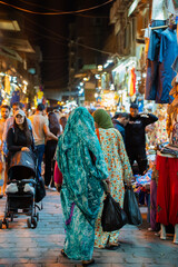 Naklejka premium Woman in a veil walking through a colorful Cairo market with traditional Arabic clothes and jewelry