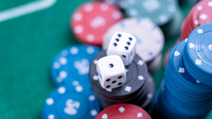 A pile of poker chips with two dice on top. The chips are of different colors and sizes, and the dice are white and black. Concept of excitement and anticipation