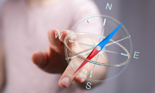 Close-up of a hand pointing towards a compass, representing guidance, direction, and exploration. Perfect for themes of decision-making, travel,