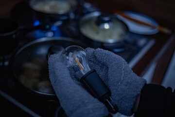 A broken lamp in a person's hands near a kitchen stove. 