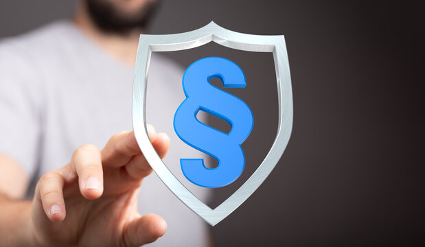 A hand presenting a blue paragraph symbol encased in a shield. Conceptual representation of law, protection, and legal services. - Powered by Adobe