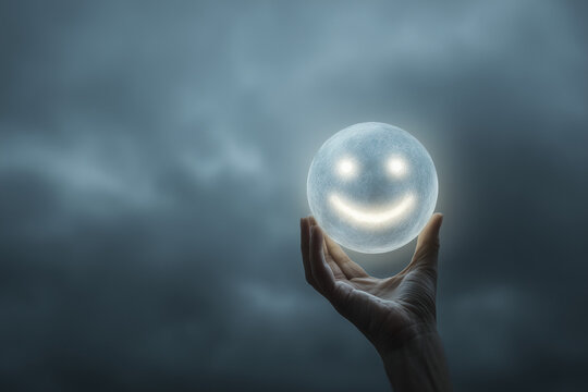 Hand holding glowing smiley face orb in dark, cloudy sky creating ethereal and hopeful atmosphere with a symbol of positivity and light, representing hope and optimism