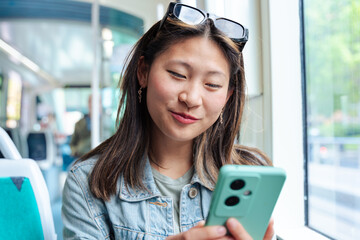 Excited woman looking at smartphone screen while traveling on public transport. Happy young female...
