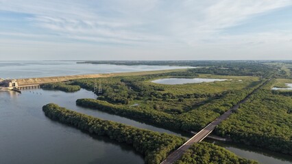 Aerial view of a dam with water and green vegetation under cloudy sky